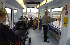 Interior of metro car with passengers as it travels above ground.