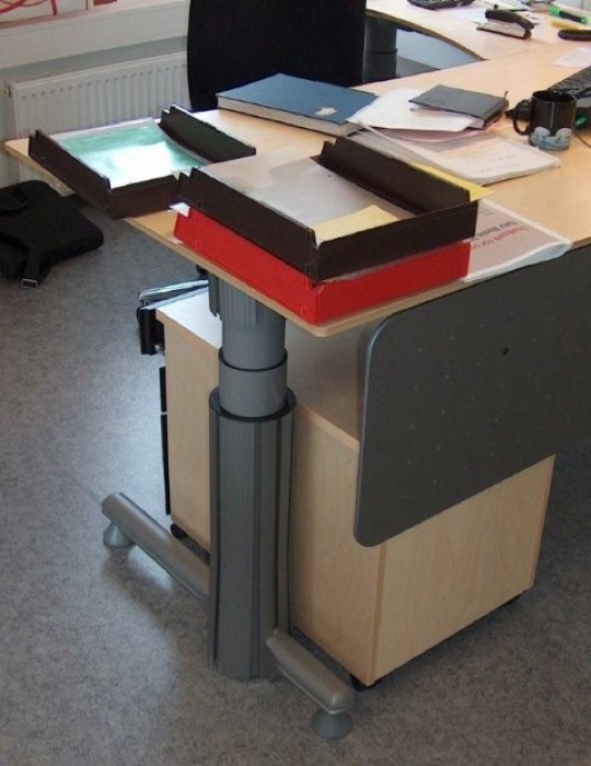 Desk with adjustable length leg and small filing cabinet stowed beneath it