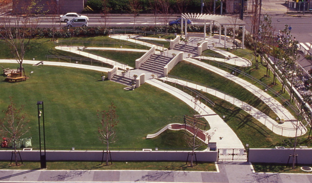 aerial view of large green space cross cut by flat paths, ramps, and stairs