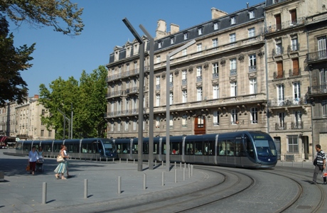 Two trams rounding a curve with pedestrian traffic around