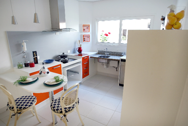 White kitchen with bright orange and red cabinet drawers and small breakfast table