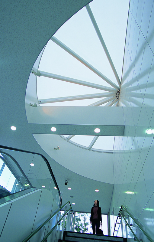 A woman at top of stairs looks up to a large semi-circle skylight.