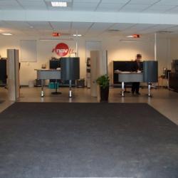 the front reception area with a dark grey rug providing a color contrast and leading visitors toward the backlit reception area with the red NAV logo visible from the entry.