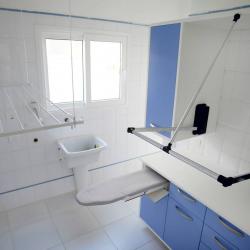 White laundry room with small sink on far wall and ironing board sticking out from cabinets on the right