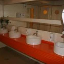 Bright orange counter with four white sinks