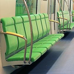 Close up of high backed seating on the subway car and curved stainless steel handgrips. 