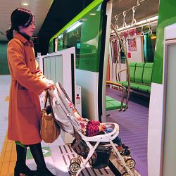 Photo of woman pushing a baby carriage across the minimal gap between the platform and train.