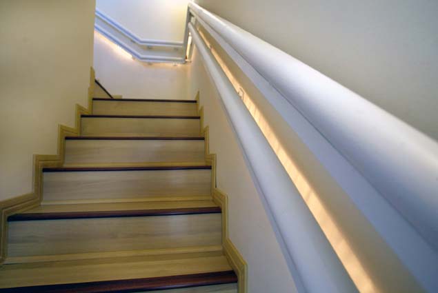 Stair with contrasting wood at the edge of each tread and two handrails on one side at different heights.